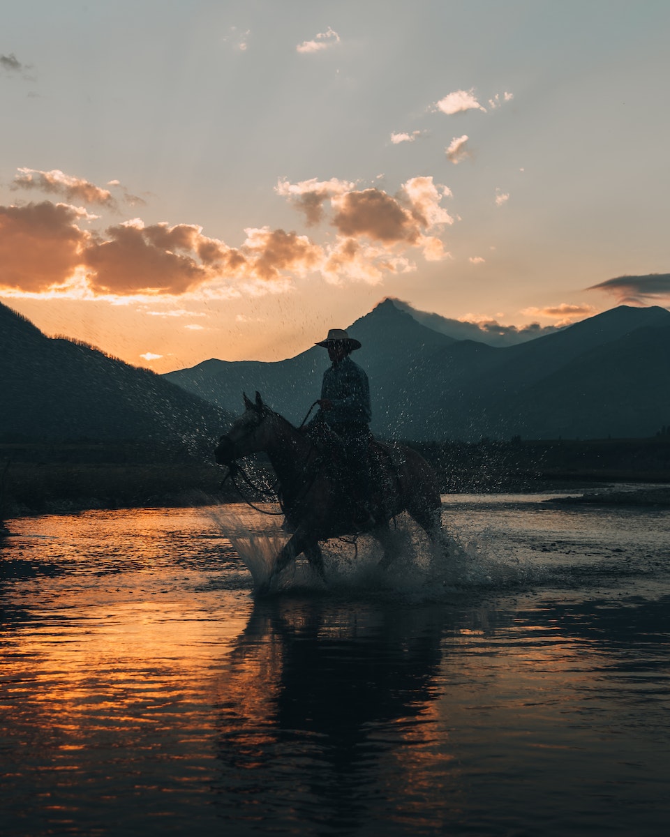 Man Riding Horse Across River