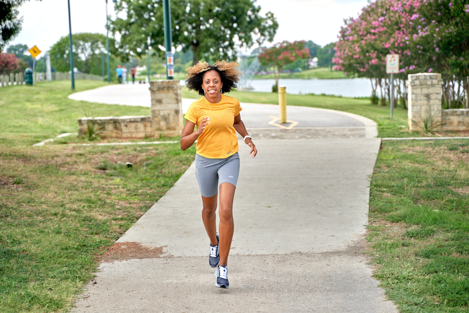 a woman running down a sidewalk in a park